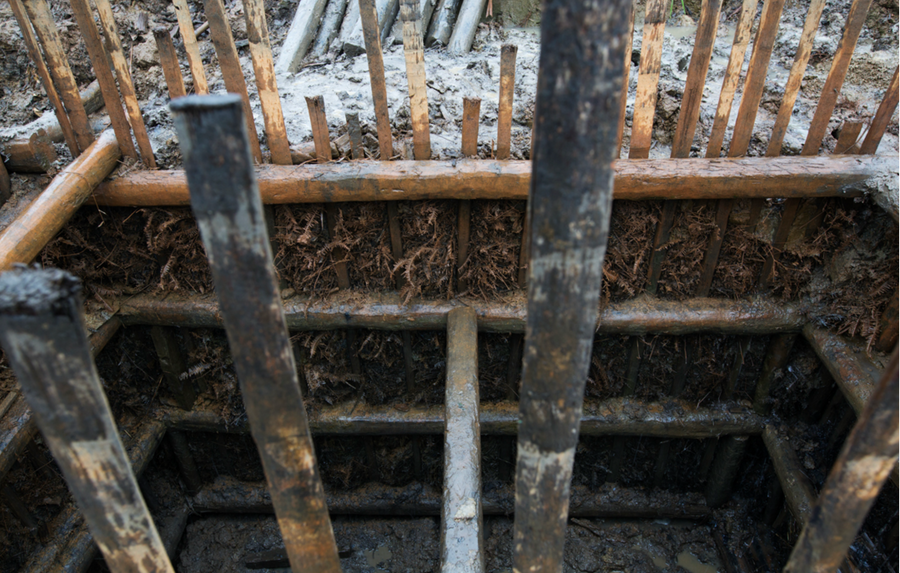 A cross section of a shallow pit, showing how local ferns are layered against the walls to hold the earth in place.